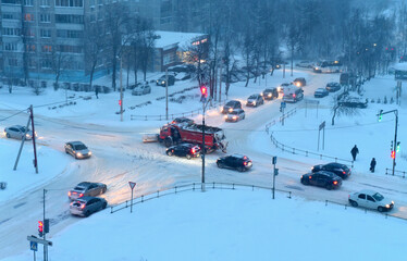 Winter, snowstorm. The streets of the city. Cars are parked at the intersection. In the center of the intersection on a snow – covered road-a sweeper. Top view.
