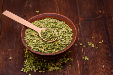 Beat green peas dry in a bowl with a wooden spoon on a wooden background. Peas as a natural product and healthy food