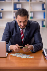 Young male employee holding banknotes in the office