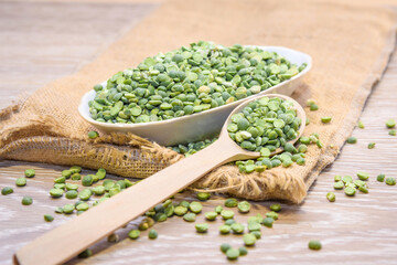 Beat green peas dry in a bowl with a wooden spoon on a wooden background. Peas as a natural product and healthy food