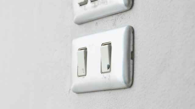 Close up young man's hand pressed the button to turn on the light switch, Open the electrical circuit beside the wall, 4K Footage.