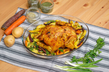 Baked whole chicken with potato and carrot in a dish