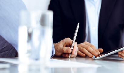 Business people using tablet computer while working together at the desk in modern office. Unknown businessman or male entrepreneur with colleague at workplace. Teamwork and partnership concept