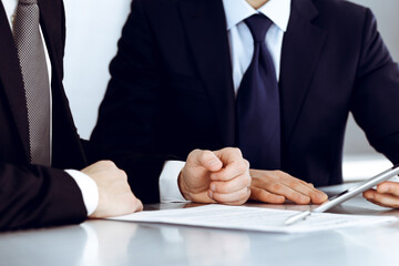 Business people using tablet computer while working together in modern office. Unknown businessman with colleague at workplace. Teamwork and partnership concept