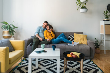 Embraced couple relaxing together on their sofa at living room in home.
Happy couple having...