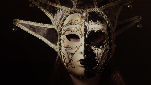 Tempting, sexy woman in mask looking at the camera. Confident, mysterious girl. Dark, theatrical, stylish place. Elegant desire.