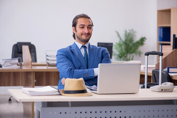 Young male employee preparing for trip in the office