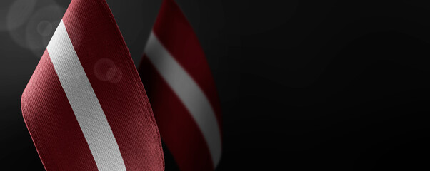 Small national flags of the Latvia on a dark background