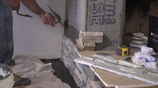 Worker Setting Stacked Stone Tile After Applying Mortar with a Notched Trowel