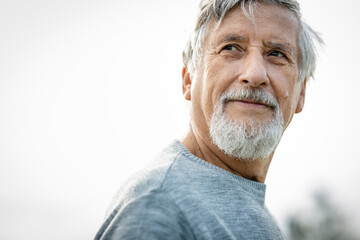 Happy senior man outdoors against the sky on a warm summer day