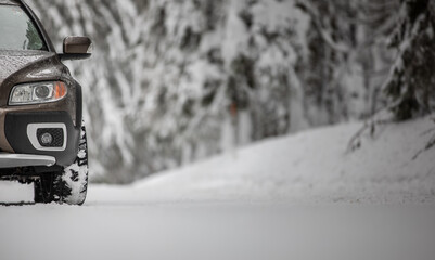 Car on a snowy winter road amid forests - using its four wheel drive capacities to get through the snow