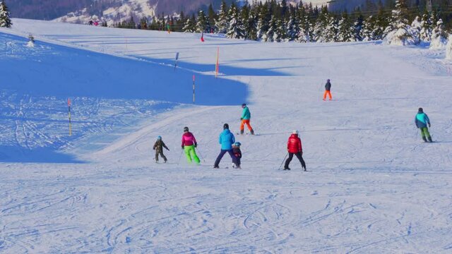 Skiers and snowboarders riding down a steep slope at a winter sports holiday resort.