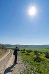Fototapeta premium Unrecognized young boy wearing sports clothes and backpack walking in the countryside.