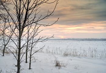 a field covered with snow at sunset