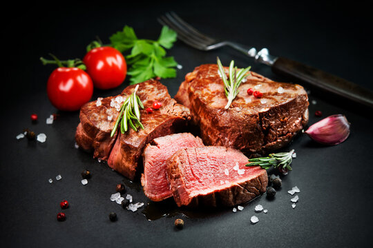 Grilled beef filet steaks with herbs and spices on dark slate
