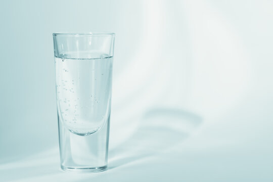 Glass of clean mineral sparkling water on a light blue background