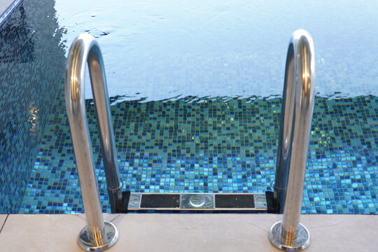 High Angle Shot Of A Stainless Steel Ladder On A Swimming Pool