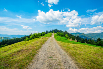 road as it goes along a mountain range in the woods on a clear day blue sky with clouds. Countryside.