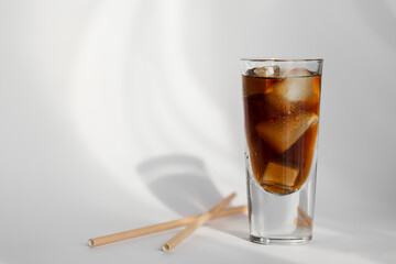 Glass of cola with ice and straw on a white background