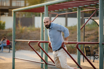 A young man with a beard performs push-ups on the uneven bars.