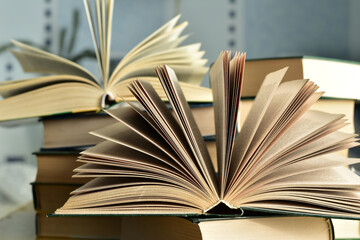 Close-up of books lying in piles, the top two are open.