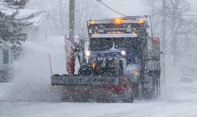 Snow plow clearing road in bad visibility with lights on