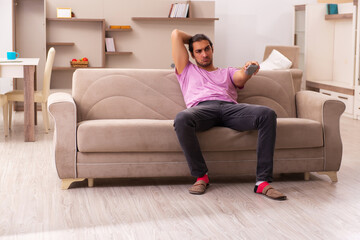 Obraz premium Young man watching tv at home during pandemic