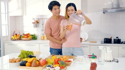 Asian couple feed each other while cooking together in modern kitchen enjoy conversation and healthy vegetarian salad food preparation. Lifestyle, happy homeowners, romantic date, hobby, love concept.