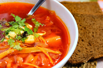 Hot rich fresh borscht, beetroot soup, with herbs, with meat, in a plate.