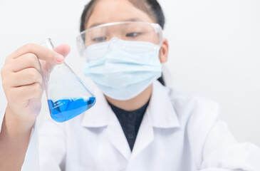 A little scientist is looking at blue liquid chemical in beaker isolated