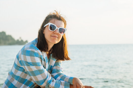 young pretty woman in sunglasses at sunset. sea on background