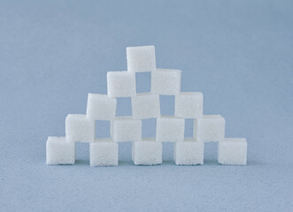 A pyramid of refined white sugar cubes on a blue background.