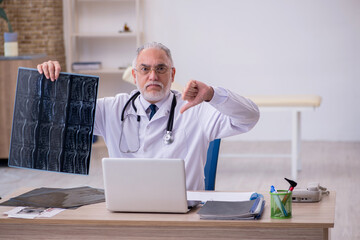 Naklejka na ściany i meble Old male doctor radiologist working in the clinic
