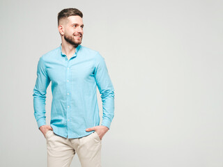 Fototapeta premium Portrait of handsome smiling hipster lumbersexual businessman model wearing casual shirt and trousers. Fashion stylish man posing against grey background in studio