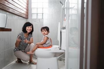 Smiling mother and baby look at the camera while watching videos on mobile phones with copyspace in...