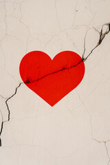 The red heart symbol is located on a crack in the wall. Vertical foto