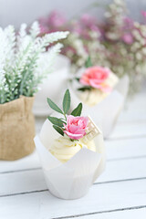 Several cupcakes and muffins with white butter cream and a lively pink rose on a white wooden table. Valentine's day or Mother's Day gift. Fresh flowers are on the table nearby. Rustic style.