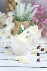 Several cupcakes and muffins with white butter cream and a lively pink rose on a white wooden table. Valentine's day or Mother's Day gift. Fresh flowers are on the table nearby. Rustic style.