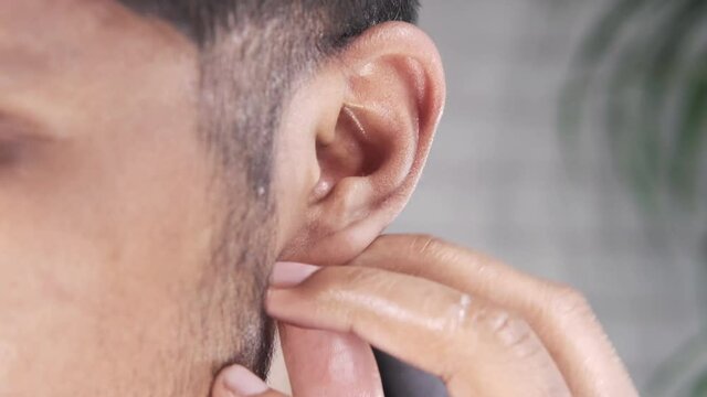 close up of young man holding ear suffering pain 