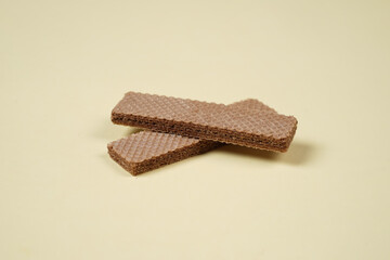 Random pile of wafers isolated on a yellow background. Chocolate biscuit wafers filled with delicious creamy chocolate. Dry and crispy wafers ready to eat. Ready to start the day with a wafer.