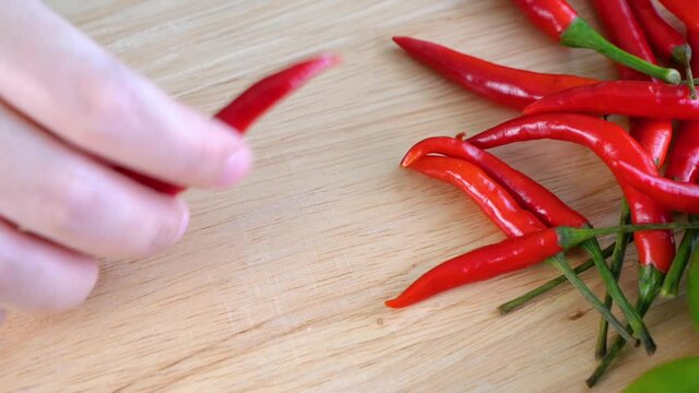 Top view shot of woman slice red chili pepper on a wooden board in the kitchen for prepare the food