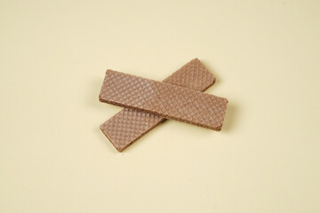 Random pile of wafers isolated on a yellow background. Chocolate biscuit wafers filled with delicious creamy chocolate. Dry and crispy wafers ready to eat. Ready to start the day with a wafer.