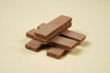 Random pile of wafers isolated on a yellow background. Chocolate biscuit wafers filled with delicious creamy chocolate. Dry and crispy wafers ready to eat. Ready to start the day with a wafer.