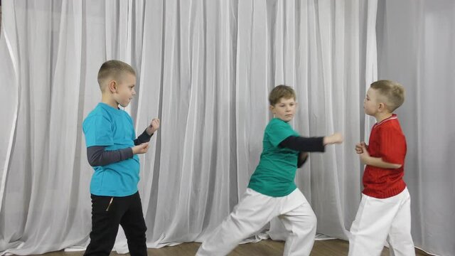 Three boys athlete in colorful t-shirts doing pair exercises