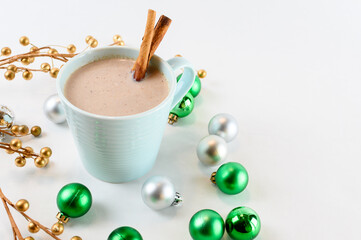 Hot chocolate in teal mug with Christmas ornaments on a white background