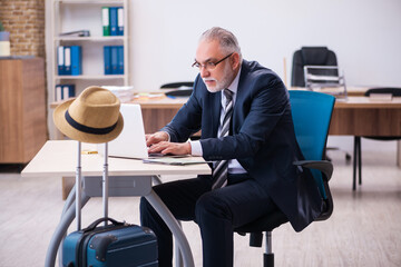 Old male employee preparing for travel in the office