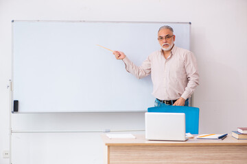 Old male teacher in the classroom in pandemic concept