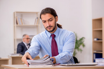 Old male boss and young employee working in the office