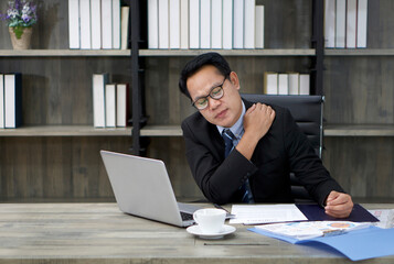 A businessman in a suit grabs the shoulder with his hands. To alleviate pain from prolonged computer use.