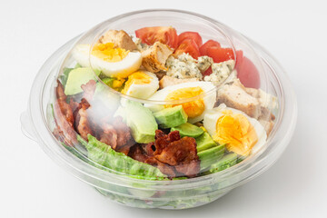 Healthy cobb salad in plastic package for take away or food delivery on white background. close up